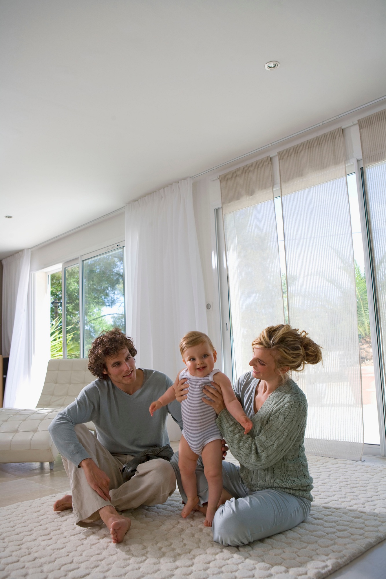 Parents help baby stand up, home