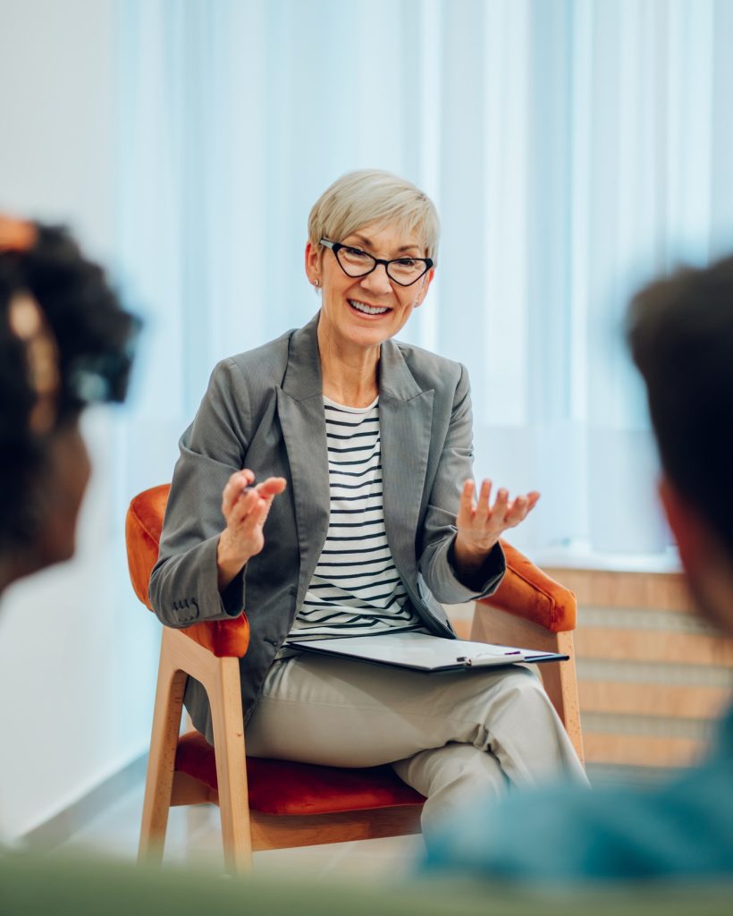 Senior woman psychiatrist talking with her patients during therapy session